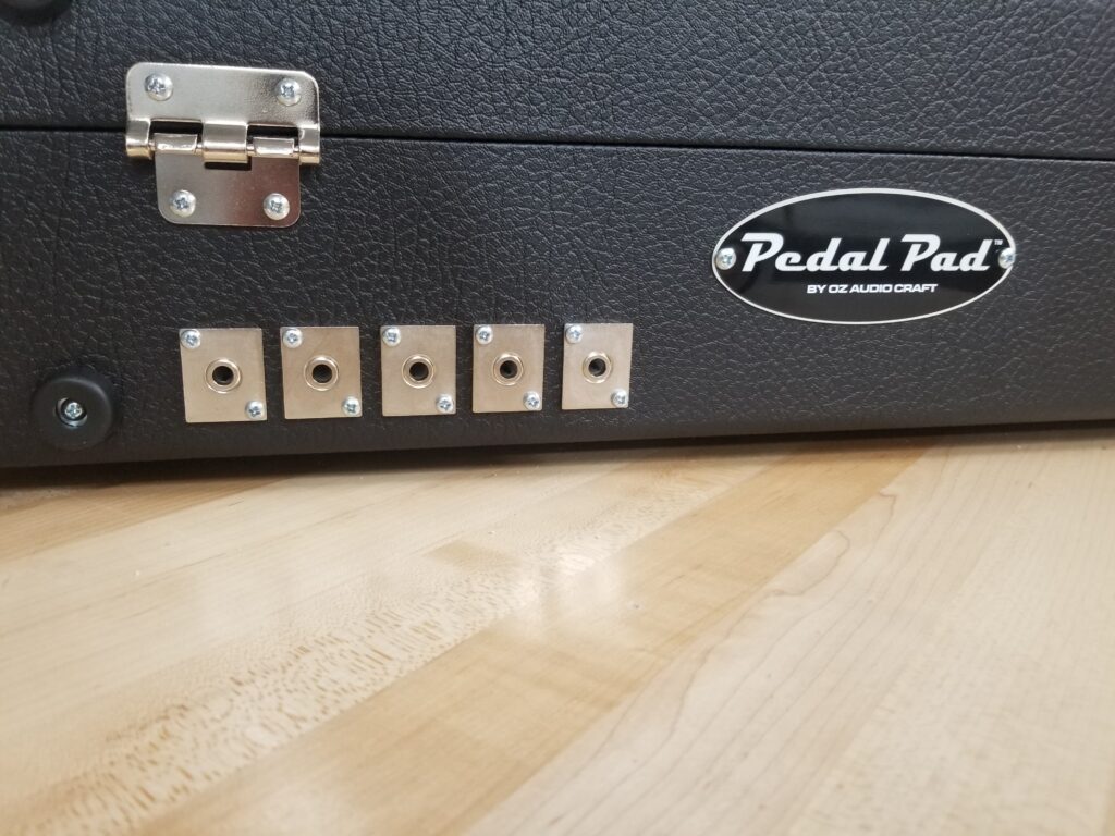 The back of a Pedal Pad custom pedalboard featuring multiple audio input and output jacks