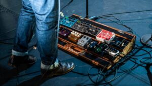 A guitar pedalboard featuring proper cable management on stage