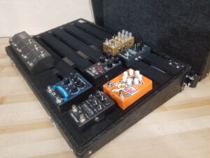 a Pedal Pad custom wood pedalboard with seven different effects pedals on the pedal deck