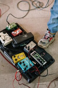 a close up of a guitar playing using their pedal board which features multiple different types of guitar effects pedals