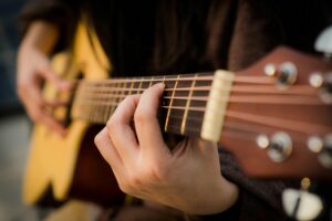 a close-up of a guitar player playing an acoustic guitar