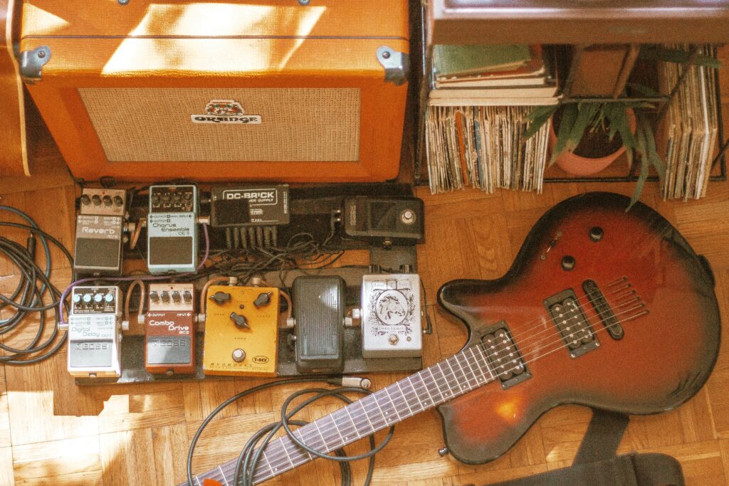 a picture of an electric guitar and pedalboard, featuring different pedals from all throughout guitar pedal history